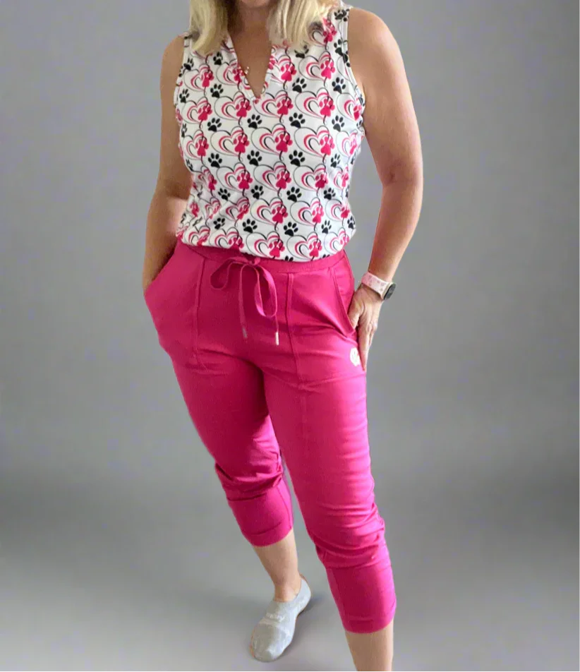 Woman in sleeveless heart and paw print top with bright pink drawstring pants, grey socks