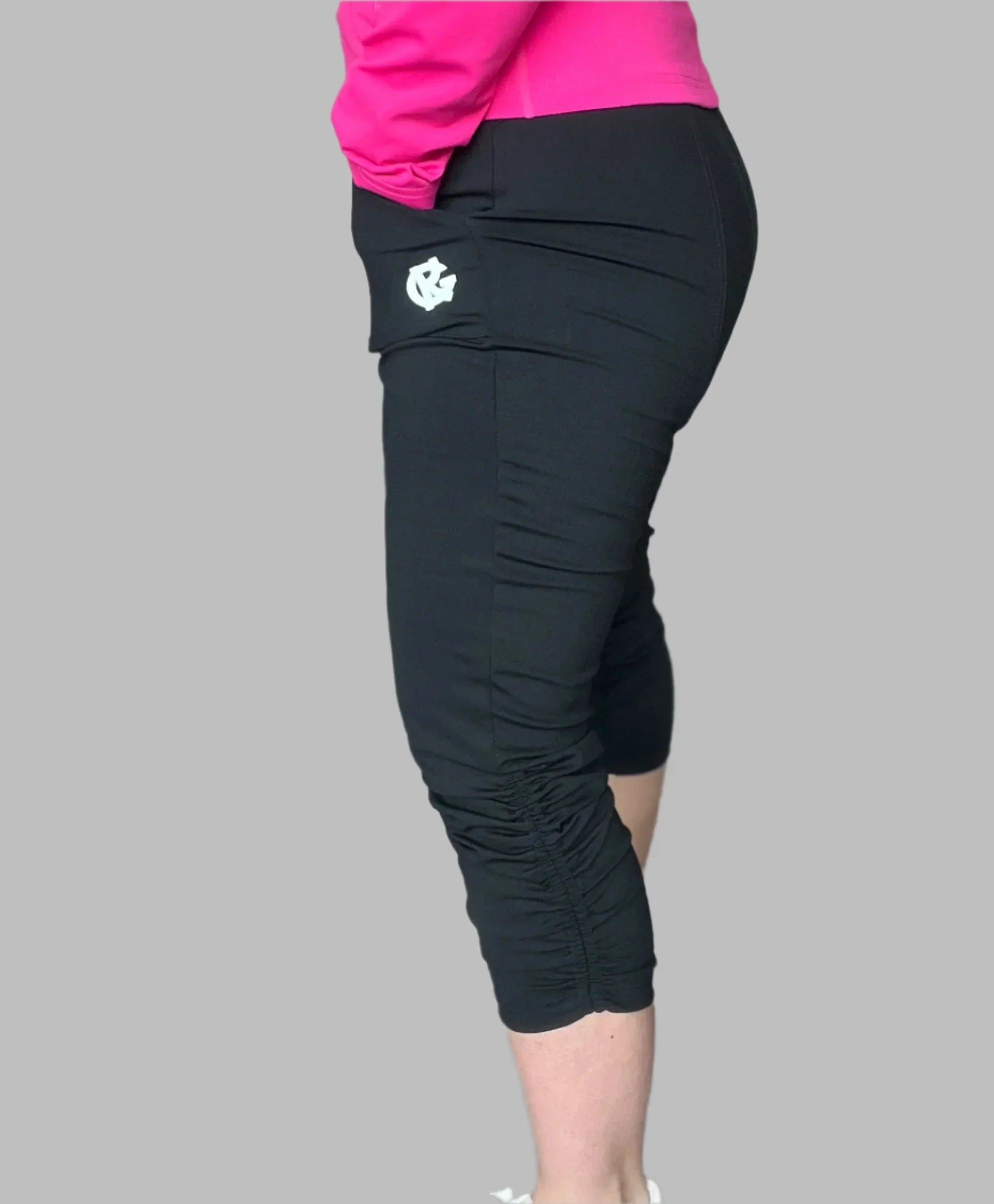 Side view of person wearing black cropped leggings with logo, pink top, gray background