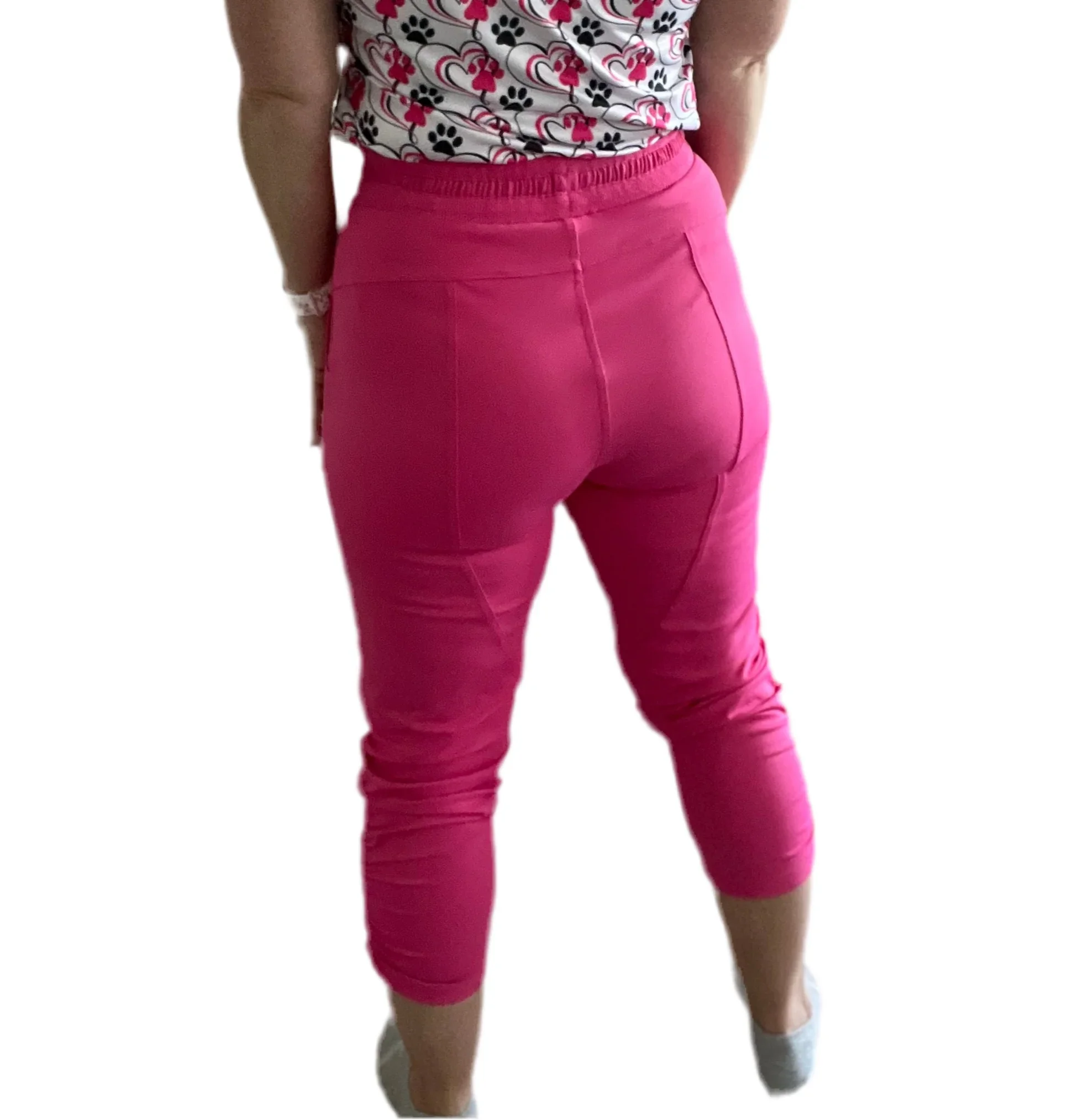 Woman wearing bright pink stretch capri pants and a white floral print shirt
