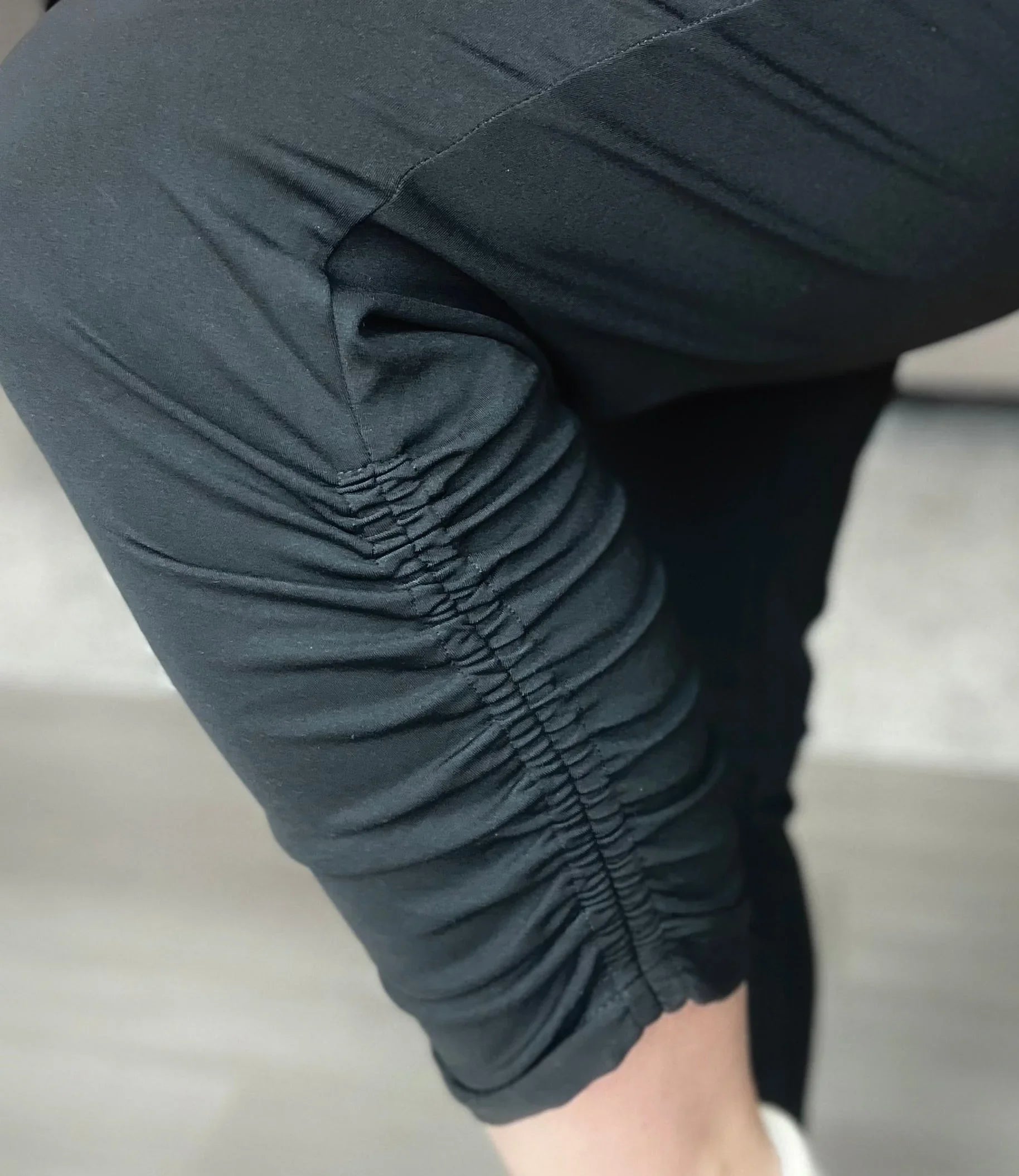 Black ruched leggings detail on knee, close-up, activewear, athleisure fashion