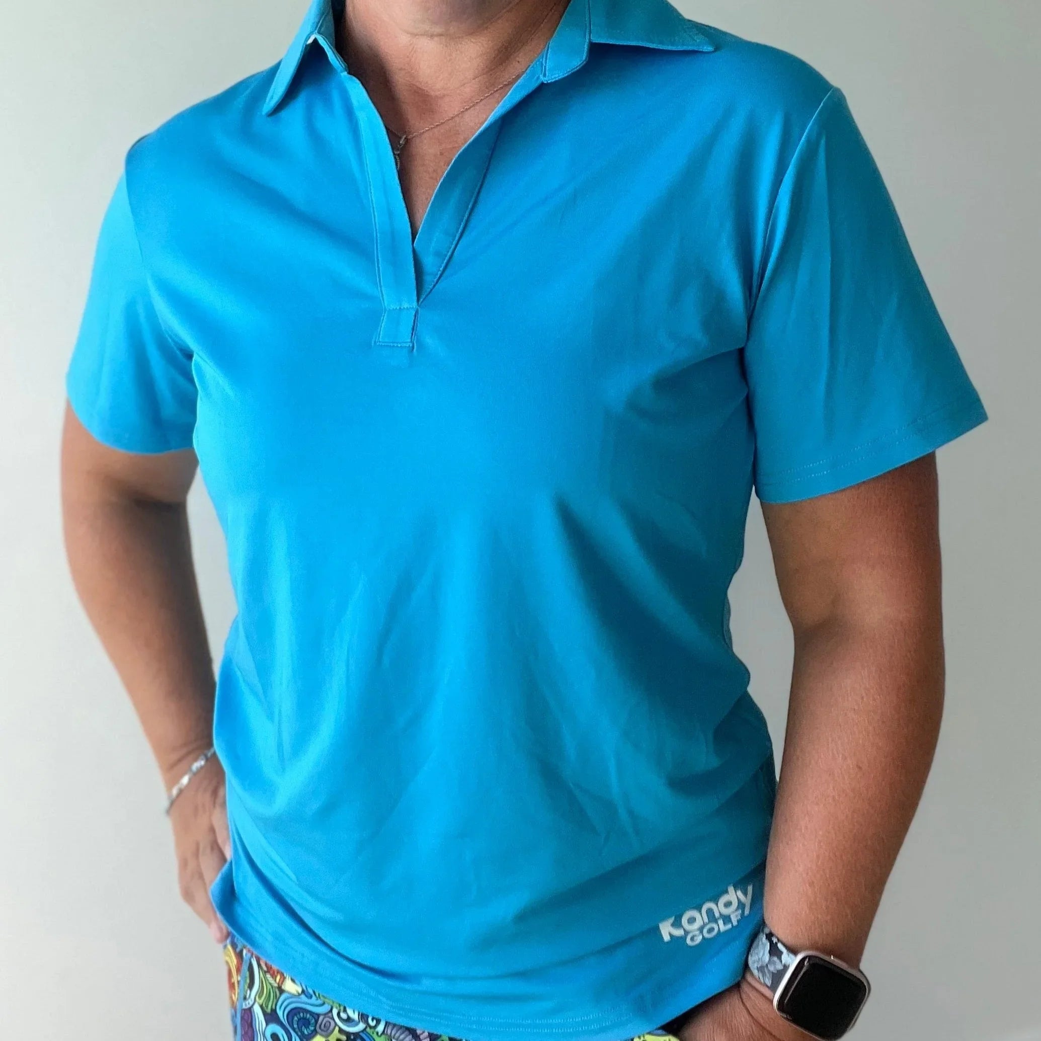 Woman wearing a bright blue Kandy Golf polo shirt and colorful patterned shorts