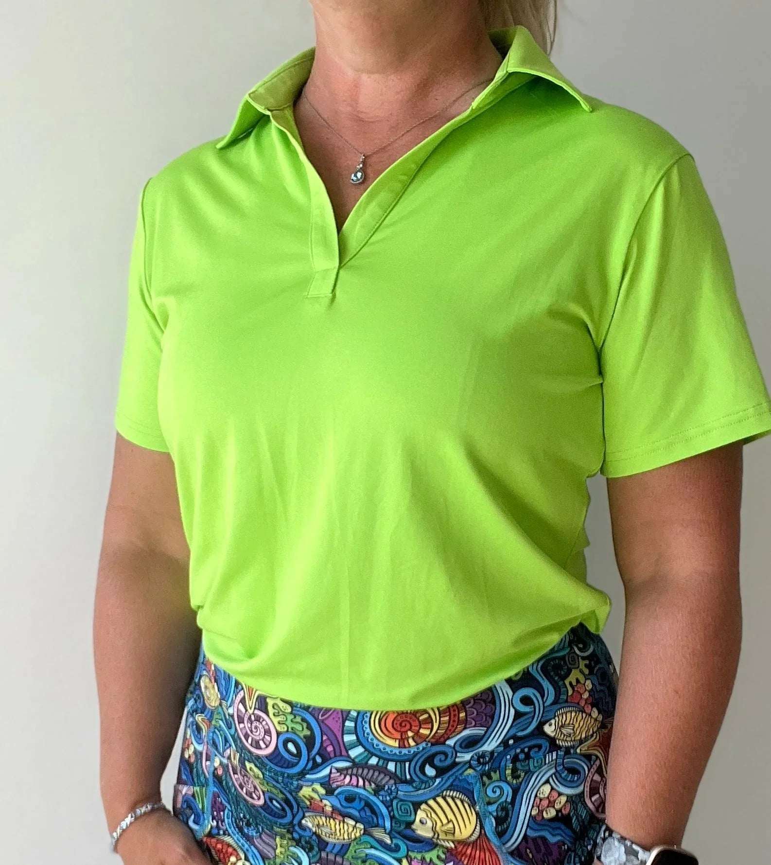 Woman wearing neon green polo shirt and colorful patterned skirt