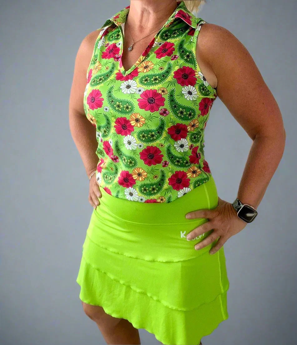 Woman wearing sleeveless floral golf shirt and bright green layered tennis skort
