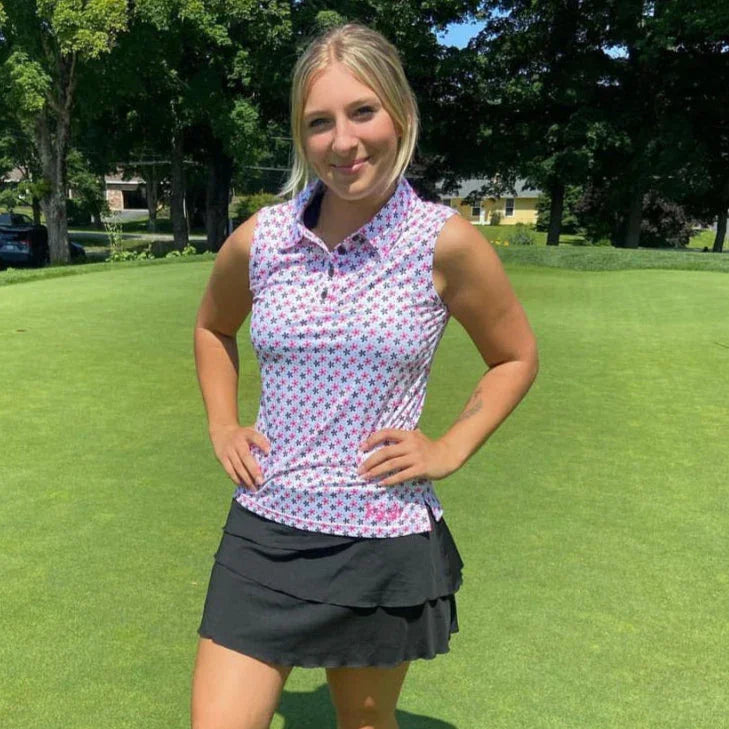 Woman golfer in sleeveless patterned polo and black skirt on sunny golf course green