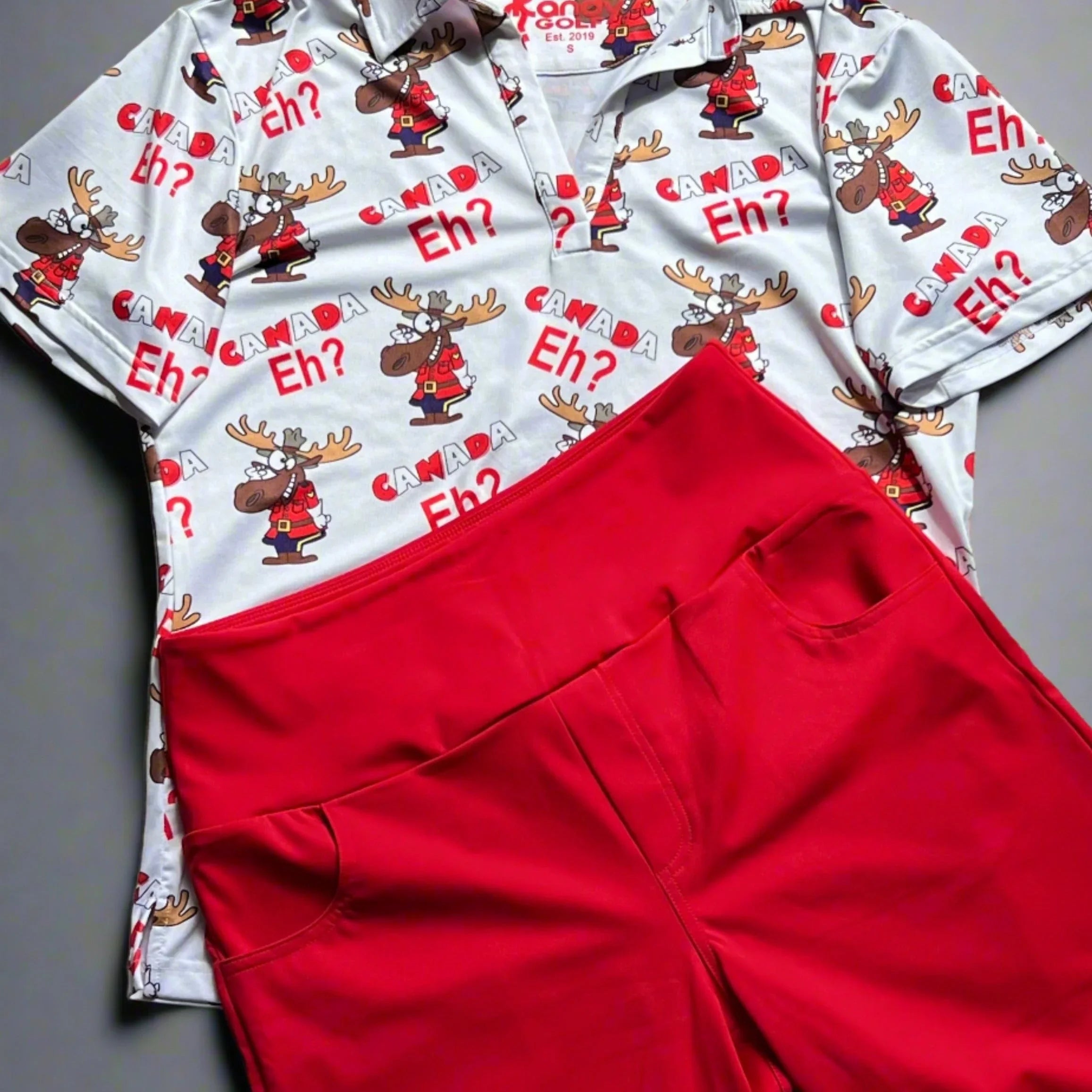 Canada Eh? moose print shirt with red pants on gray background