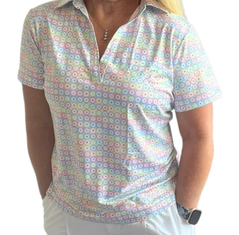 Woman wearing pastel floral print short sleeve collared golf shirt and white pants
