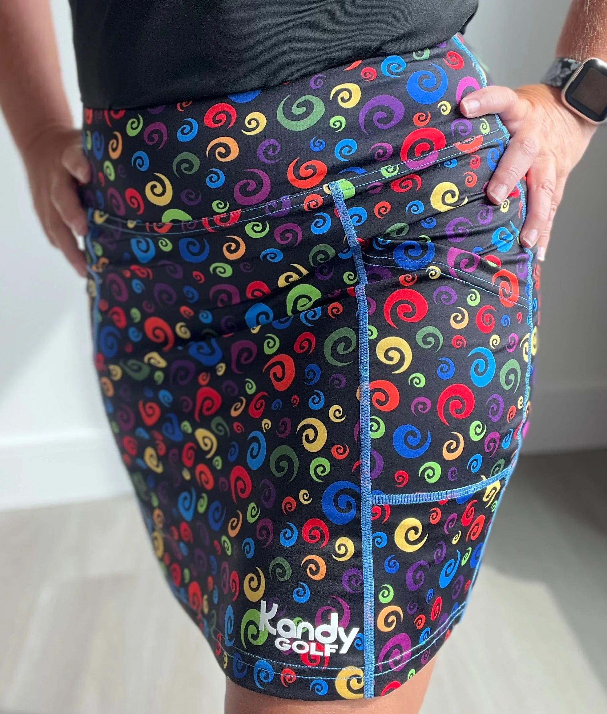 Colorful swirl print Kandy Golf skirt with pockets, worn indoors, close-up view
