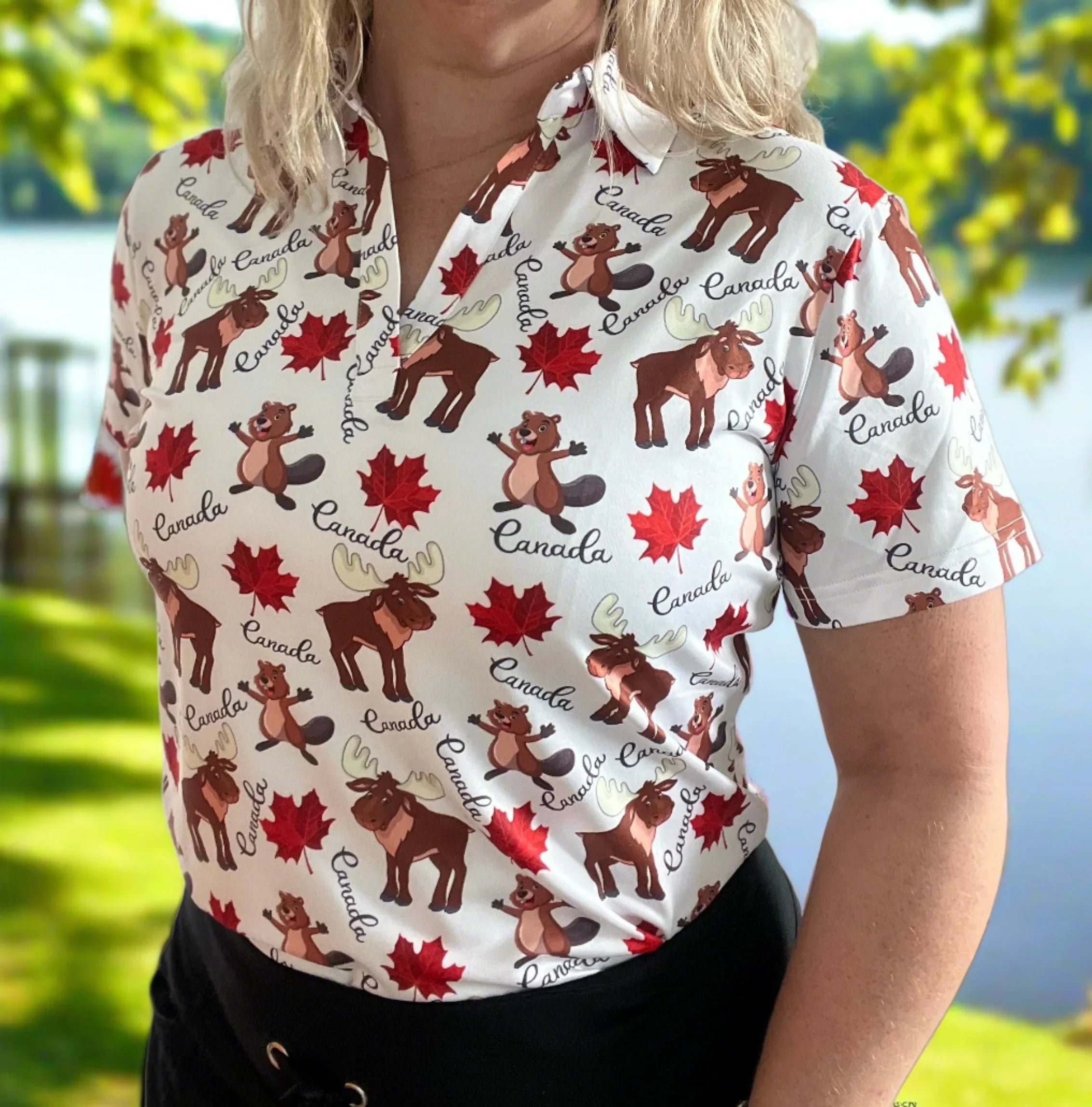 Woman wearing Canada-themed shirt with cartoon beavers, moose, and red maple leaves outdoors