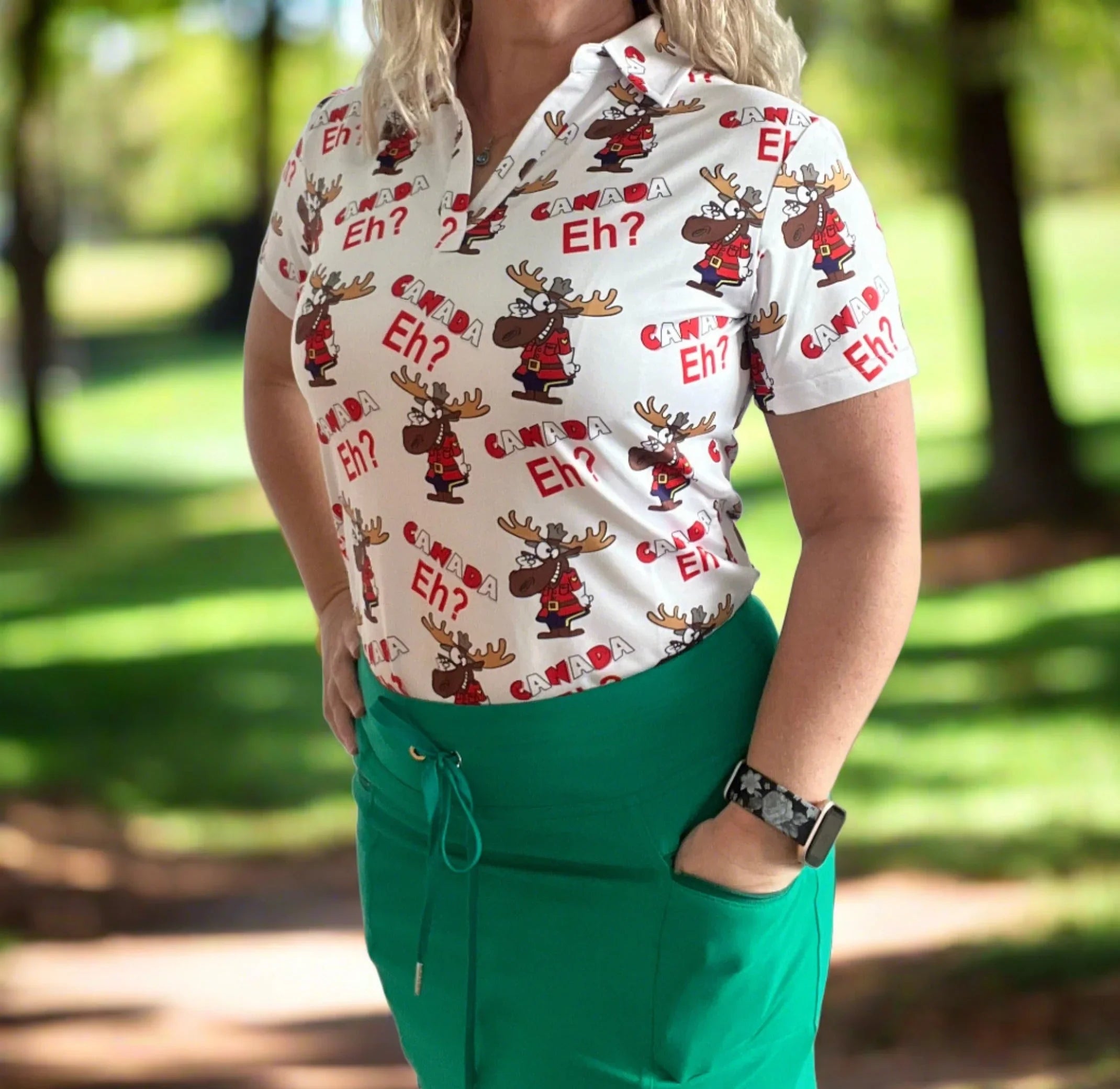 Woman wearing Canada Eh? moose print polo shirt and green skirt outdoors
