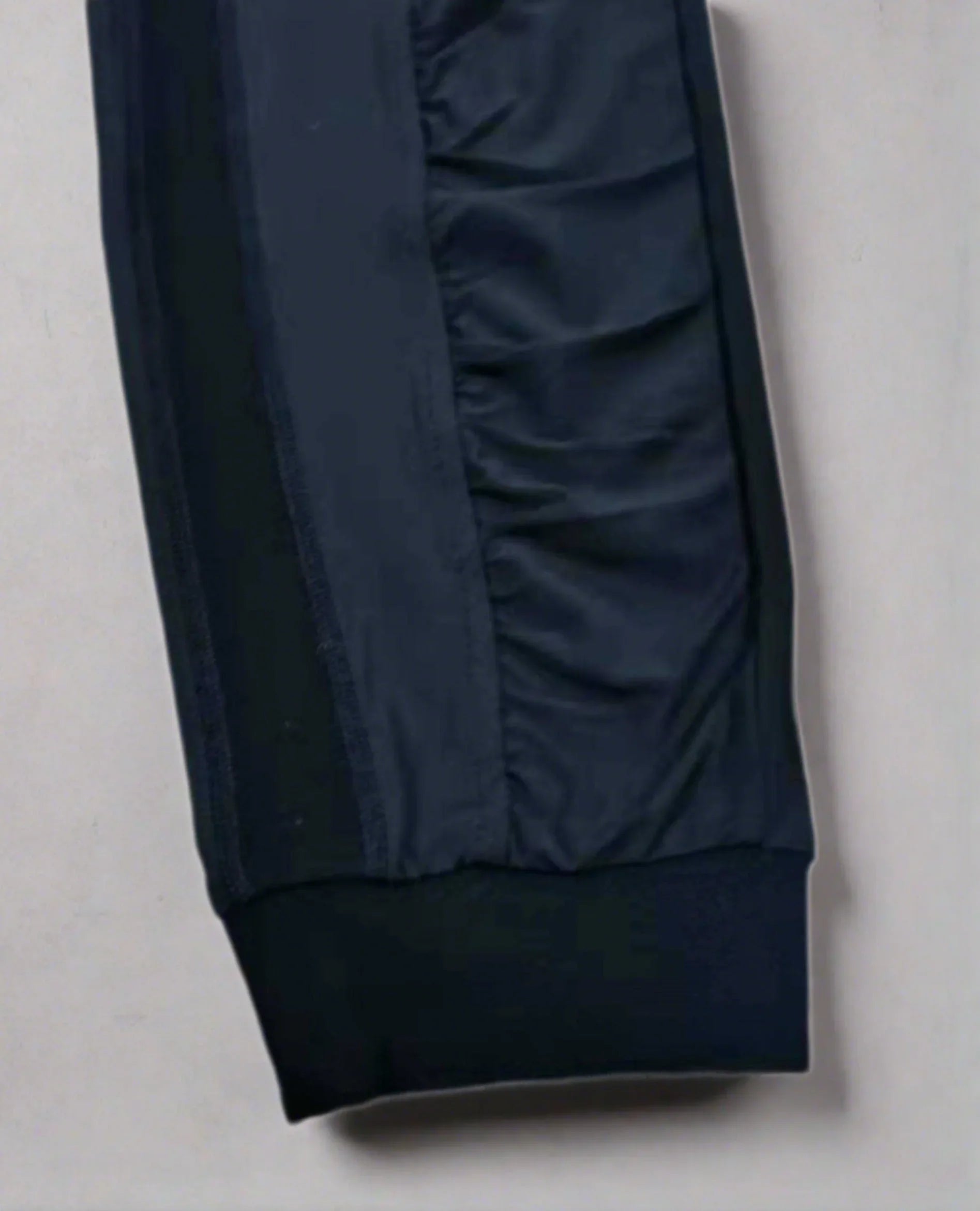 Close-up of navy blue jogger pant leg with ribbed cuff and side panel detail