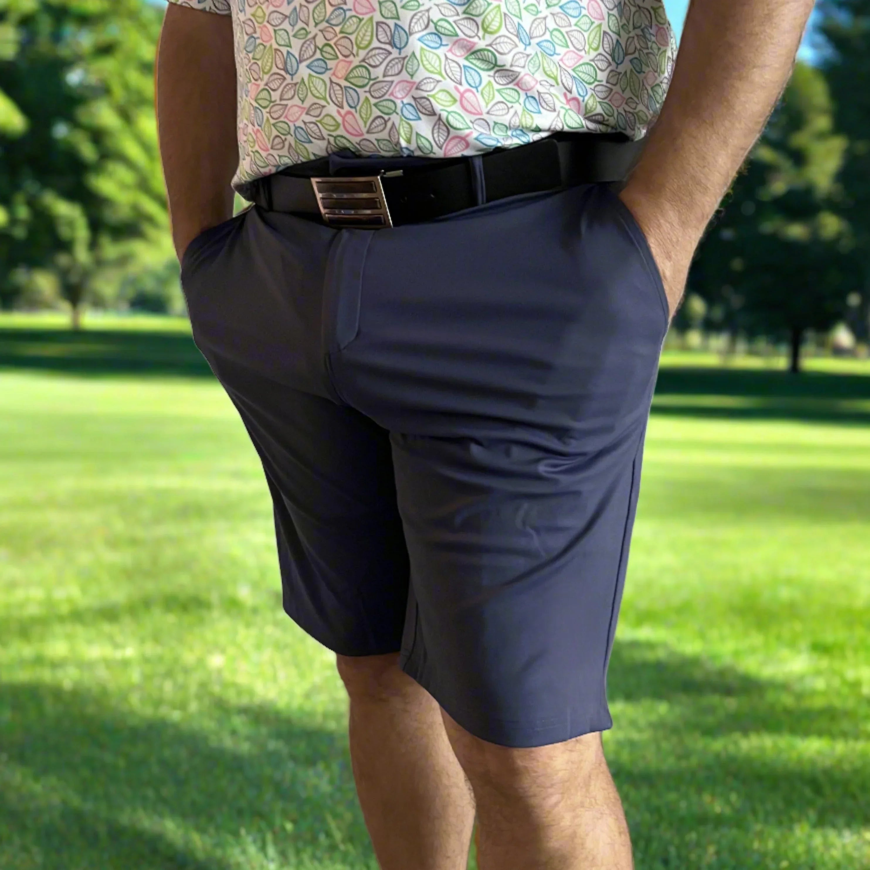 Man in navy golf shorts and leaf-print shirt on a sunny golf course