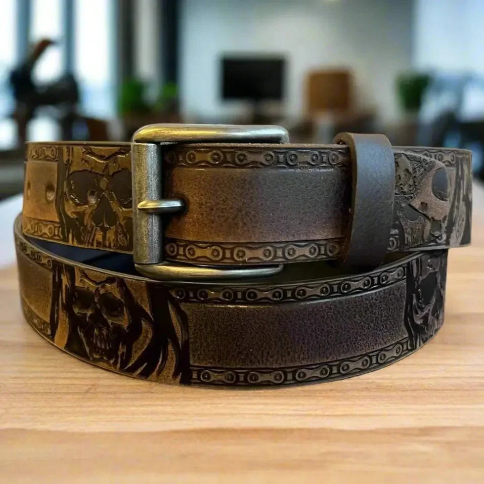 Brown grain leather men's belt with embossed skull design and metal buckle on wood surface