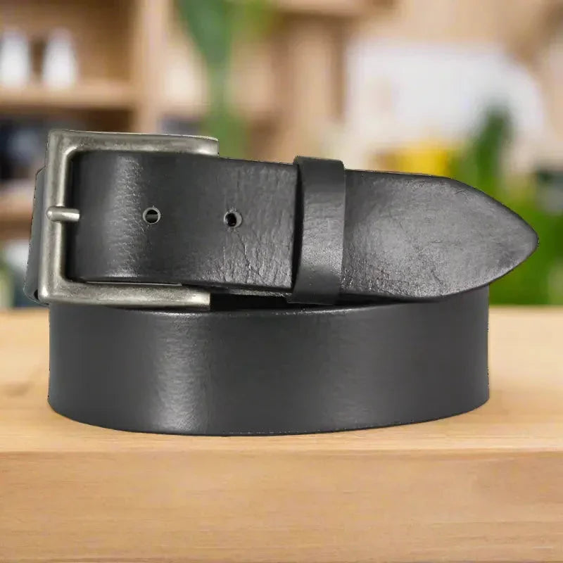 Black solid leather men's belt with metal buckle on wooden surface