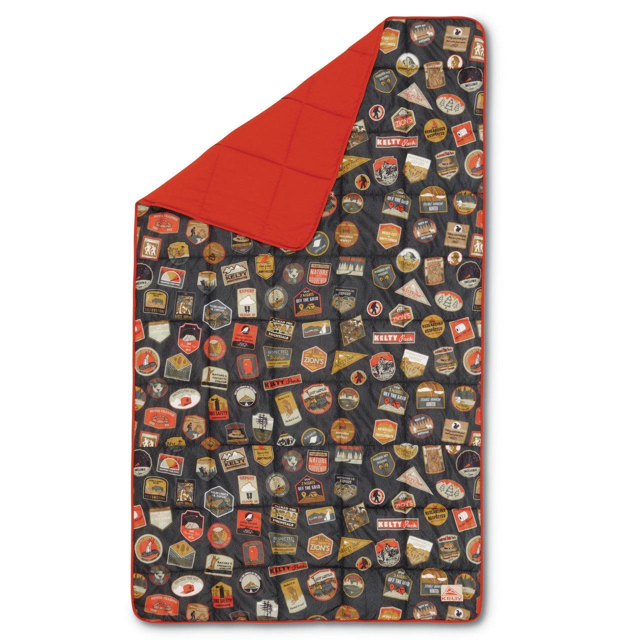 Camping-themed quilt with colorful patch and badge designs, red lining, outdoor blanket