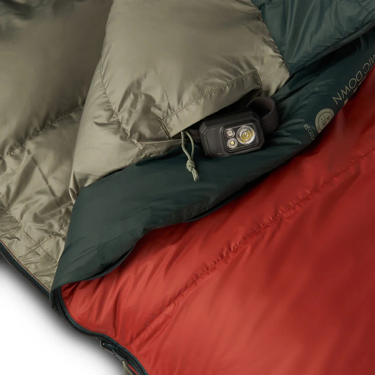Kelty Cosmic Down sleeping bag with red lining and a black headlamp inside