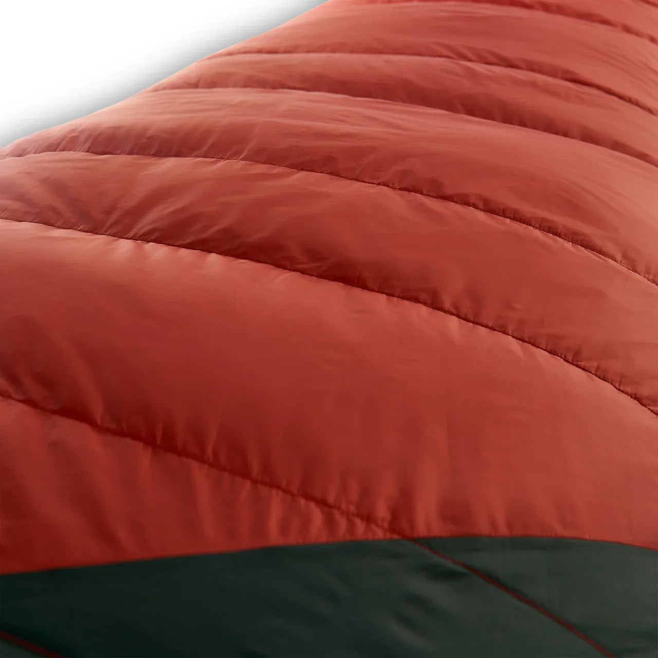 Close-up of an orange and dark green puffy down sleeping bag, outdoor gear