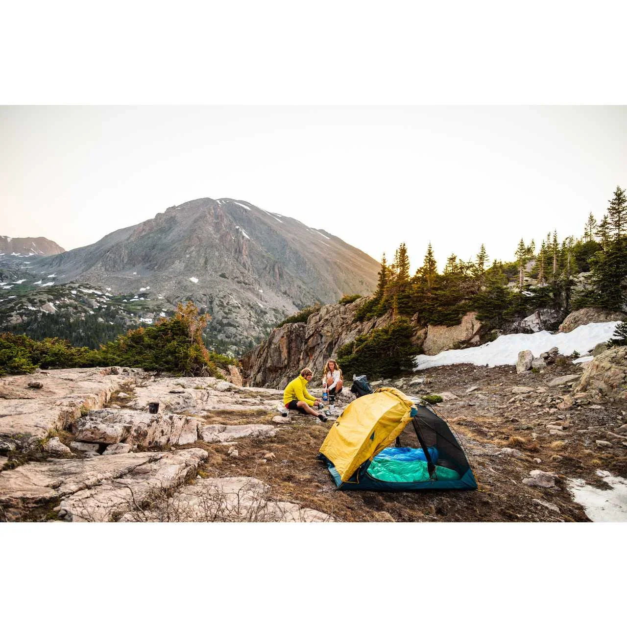 Kelty Far Out 2 tent set up on rocky mountain landscape with two campers at sunset