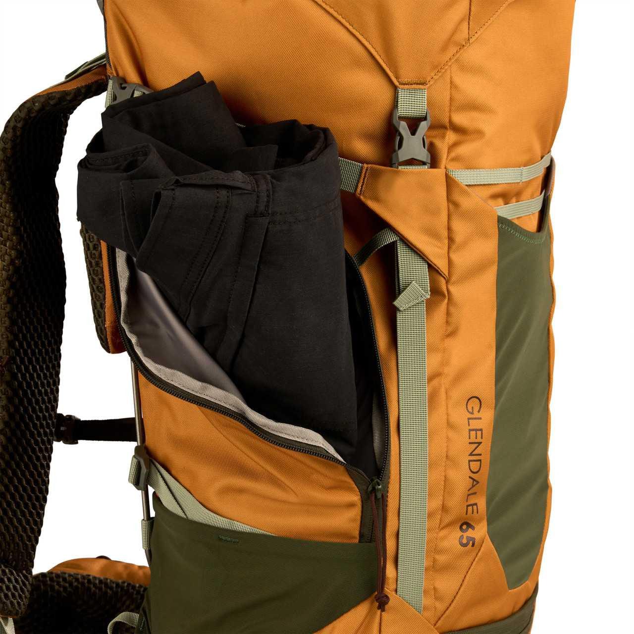 Kelty Glendale 65L orange and green backpack with side pocket holding black pants