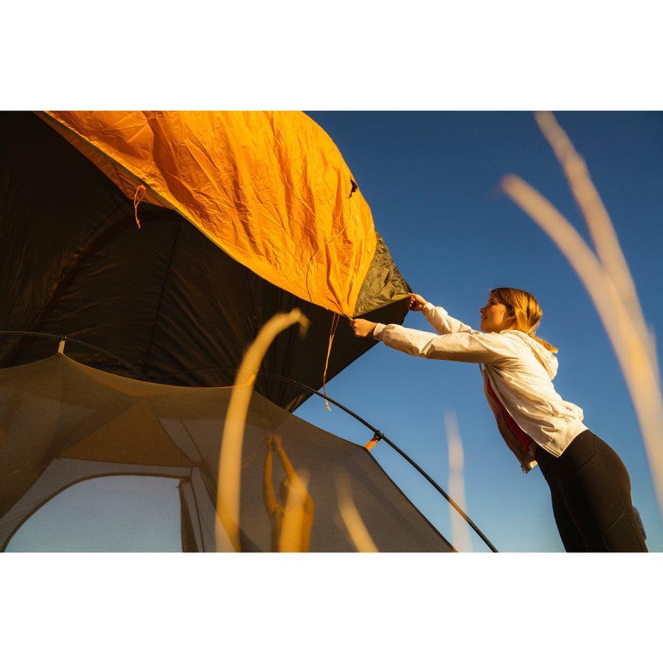 Woman setting up Kelty Grand Mesa 2 backpacking tent outdoors under blue sky