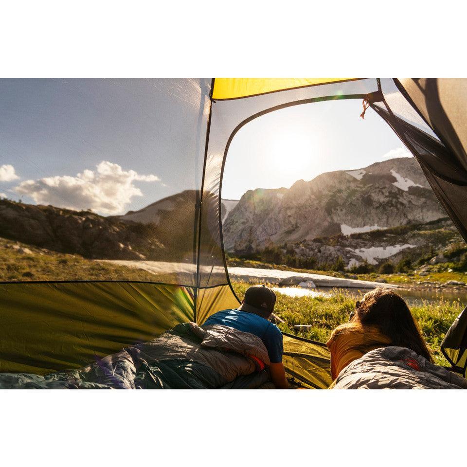Campers in sleeping bags inside Kelty Grand Mesa 2 tent with mountain view at sunrise