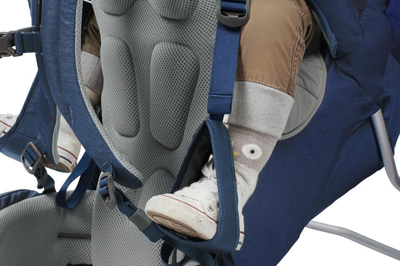Close-up of child’s feet in stirrups in blue hiking child carrier backpack, padded seat visible