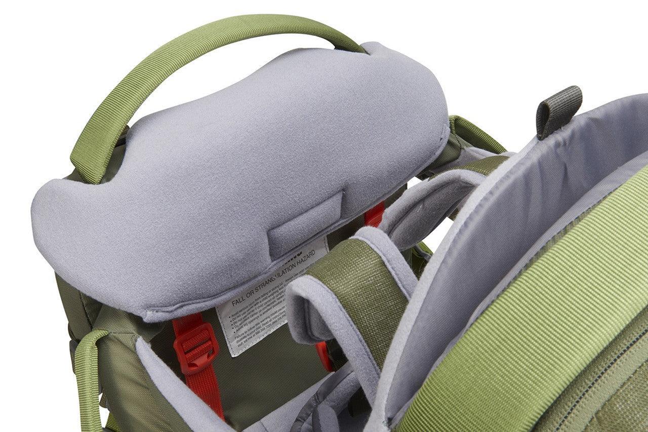 Close-up of green and gray baby carrier with padded headrest and adjustable straps.