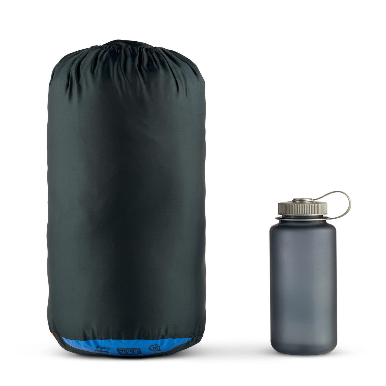 Dark navy compressible sleeping bag in stuff sack beside a gray water bottle on white background