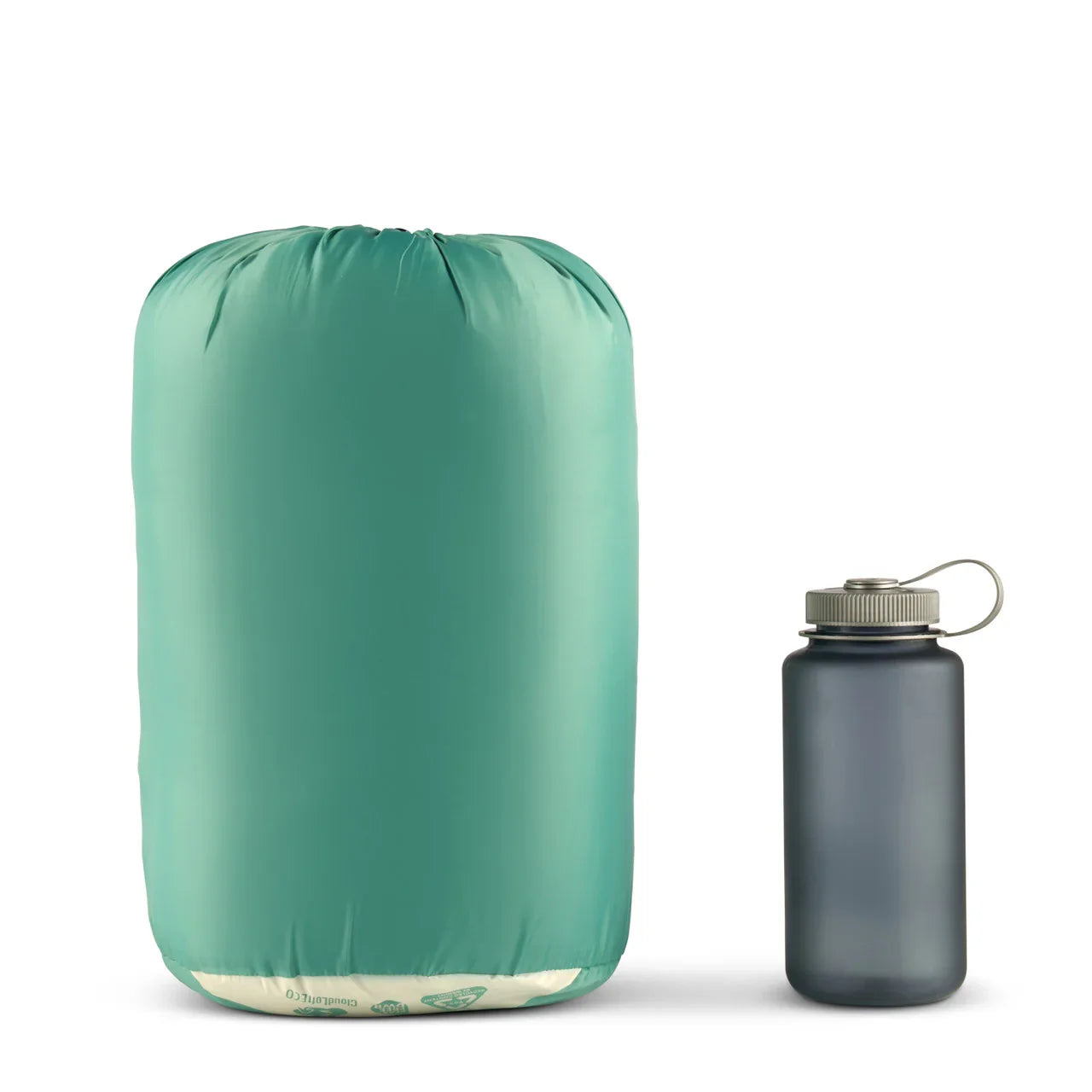 Green compression sack next to a gray water bottle on white background for camping gear comparison
