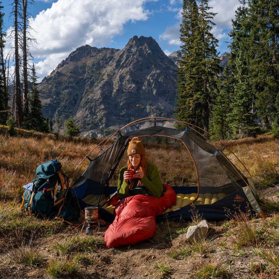 Kelty Late Start 1P tent set up in a mountain campsite with hiker and backpack