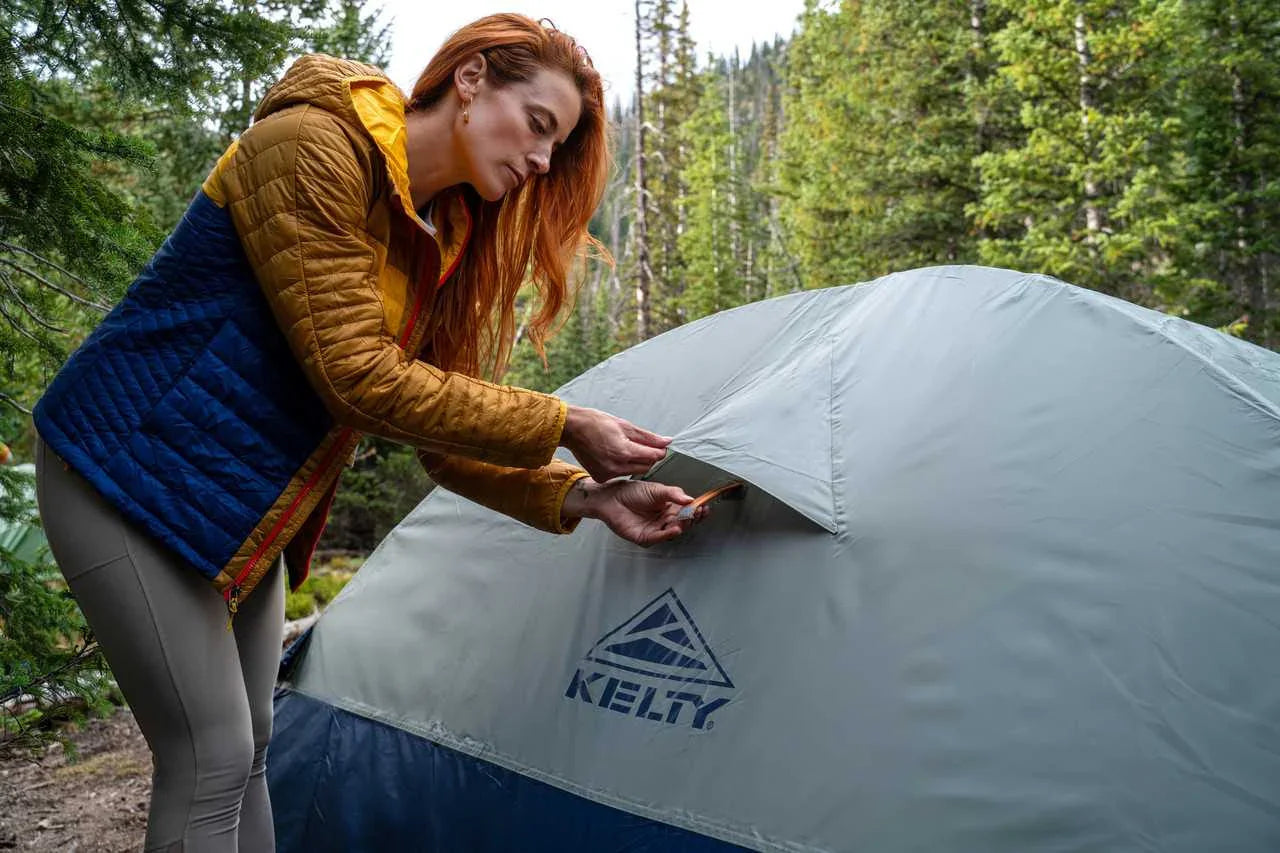 Woman setting up Kelty Late Start 1P Tent in forest camping scene