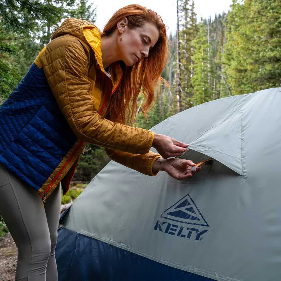 Woman setting up Kelty Late Start 2P tent in forested outdoor camping area