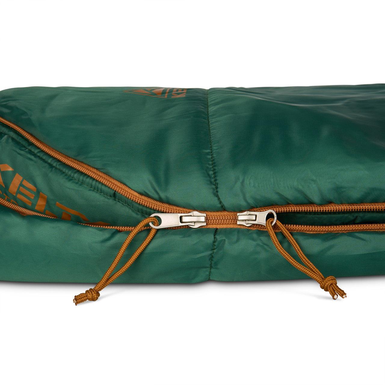 Green sleeping bag with orange zippers and Kelty logo, close-up on fabric and zipper