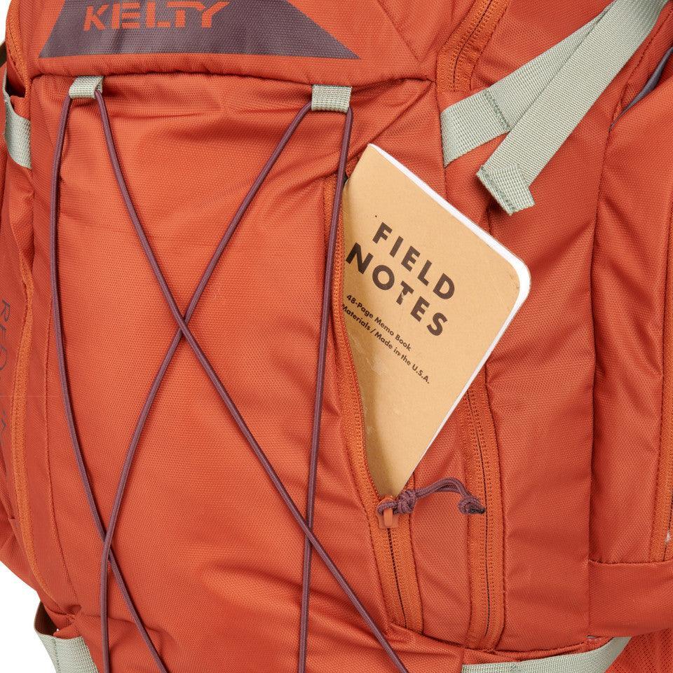 Close-up of Kelty Redwing 36 women's backpack in orange with Field Notes notebook in front pocket