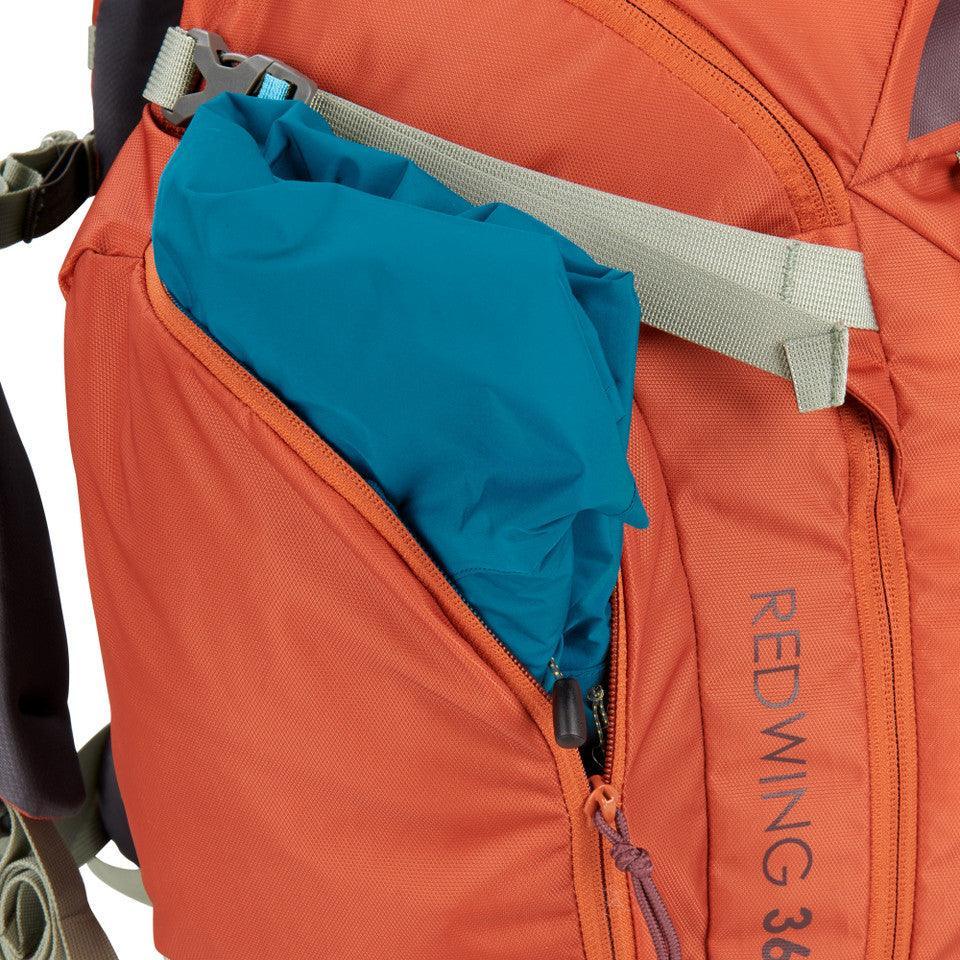 Kelty Redwing 36 women's backpack in orange with side pocket holding a blue item.
