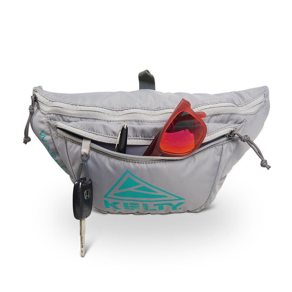 Kelty Warbler gray fanny pack with sunglasses, keys, and pen in front zipper pocket