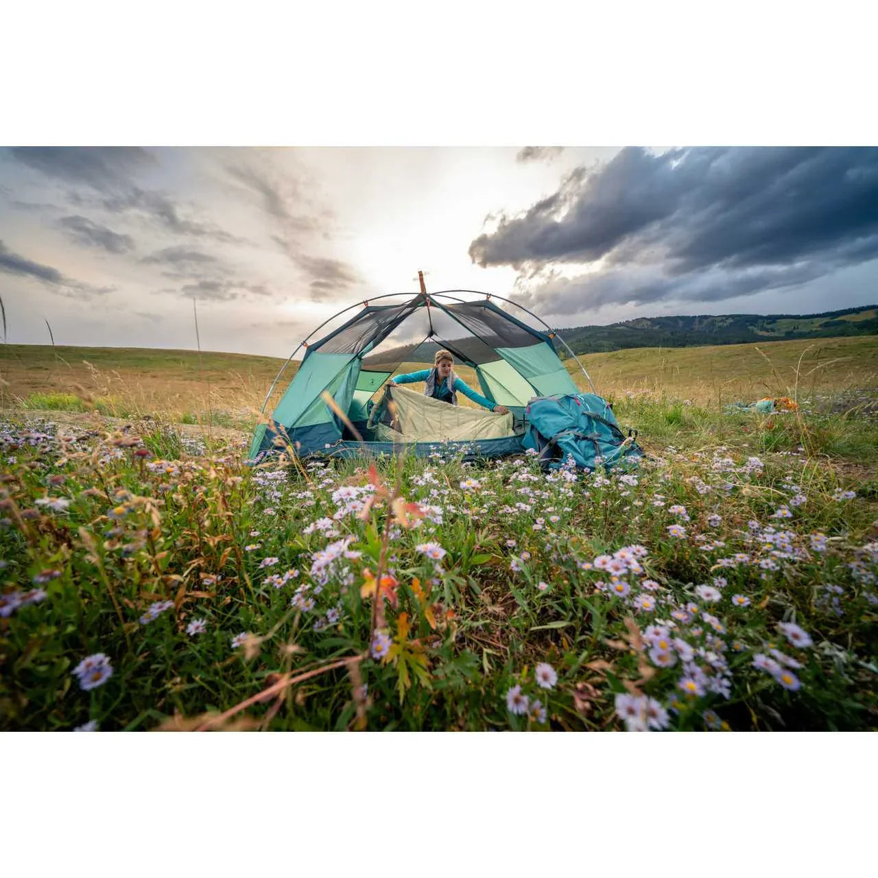 Kelty Wireless 2 tent set up in a wildflower meadow at sunset with a camper inside