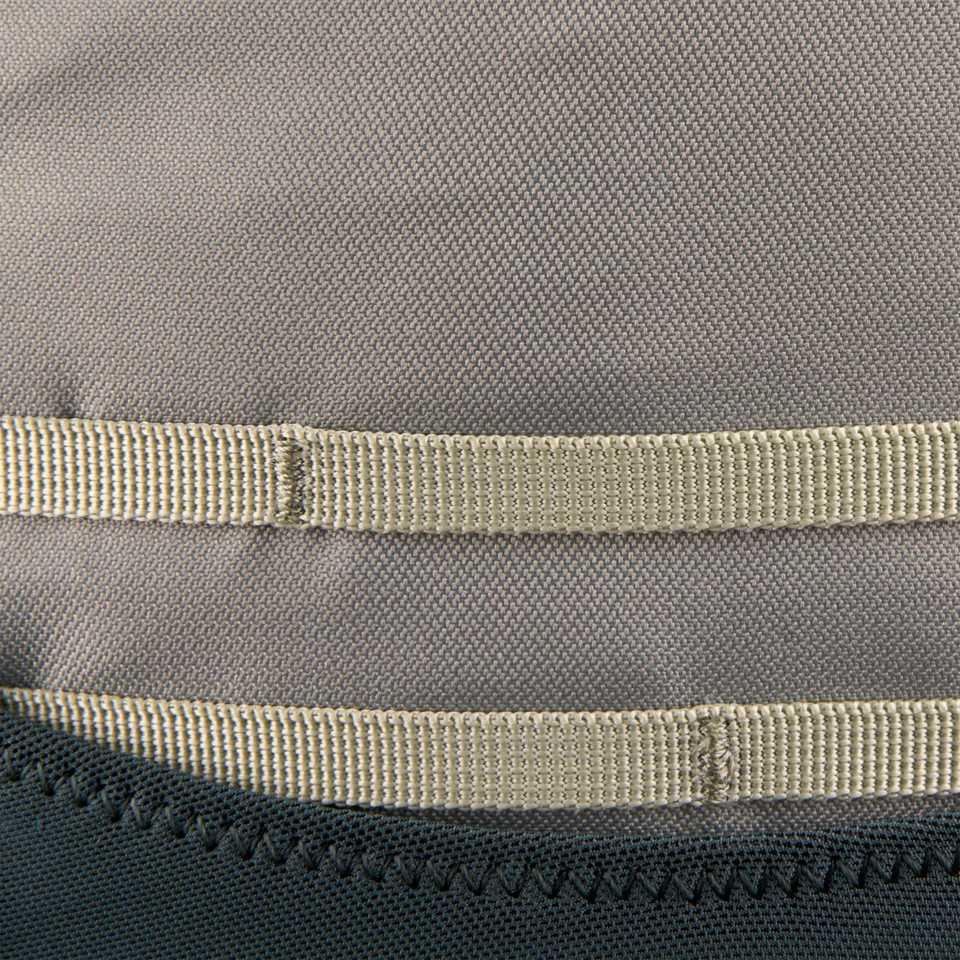 Close-up of durable grey backpack fabric with beige webbing detail and stitching