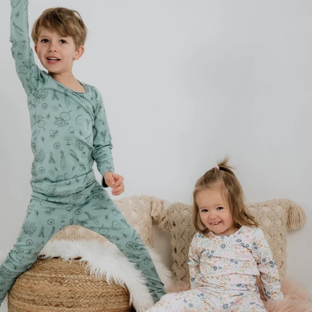 Kids wearing bamboo lounge set pajamas, sitting on pillows in cozy room