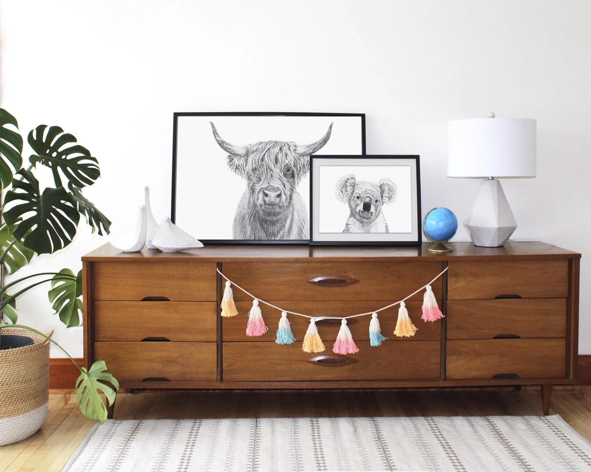 Framed koala portrait drawing on a wooden dresser with modern decor and tassel garland