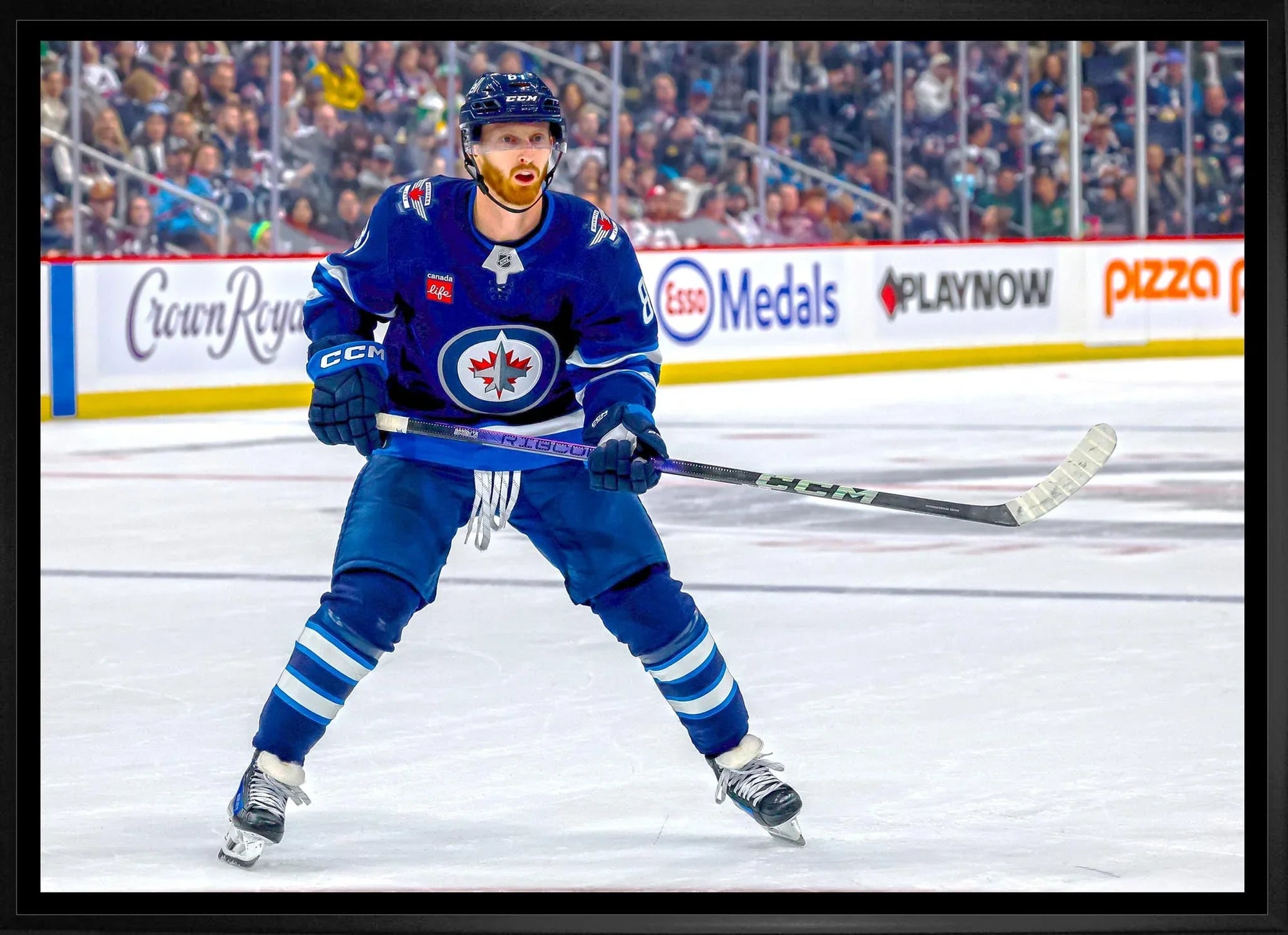 Winnipeg Jets hockey player on ice rink during game, wearing blue uniform and helmet.