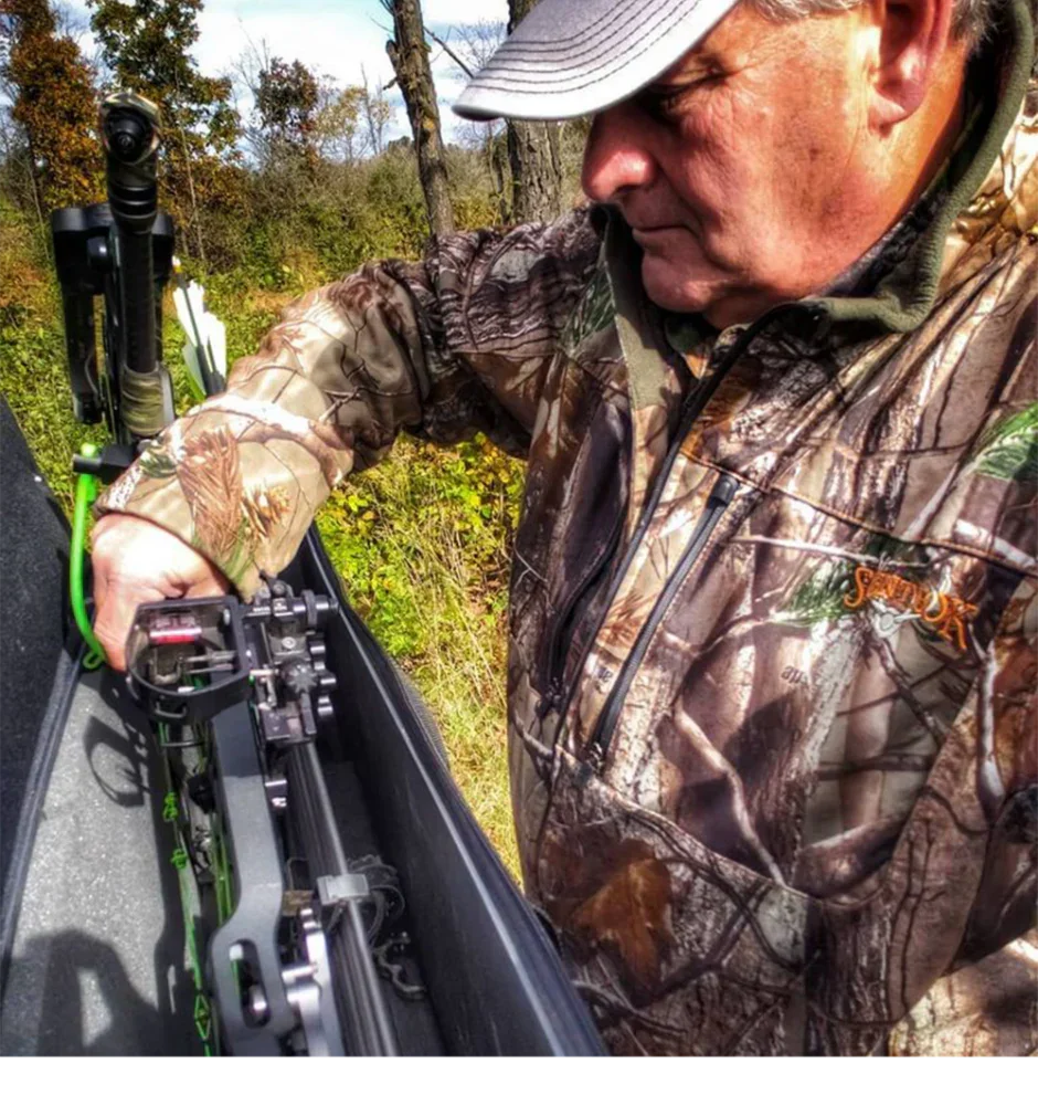 Hunter in camo jacket with crossbow outdoors in forest setting