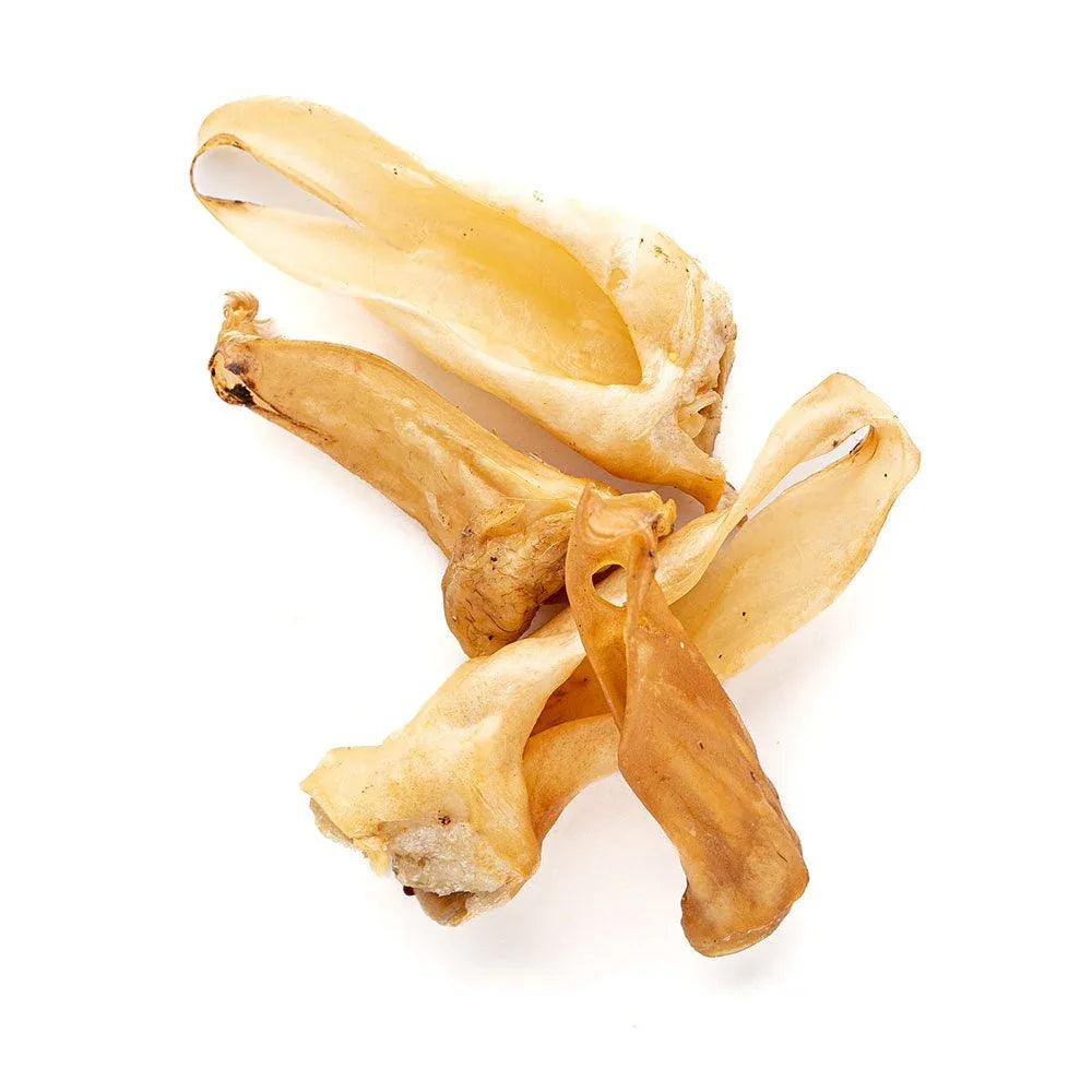 Dried lamb ear dog chews arranged on a white background