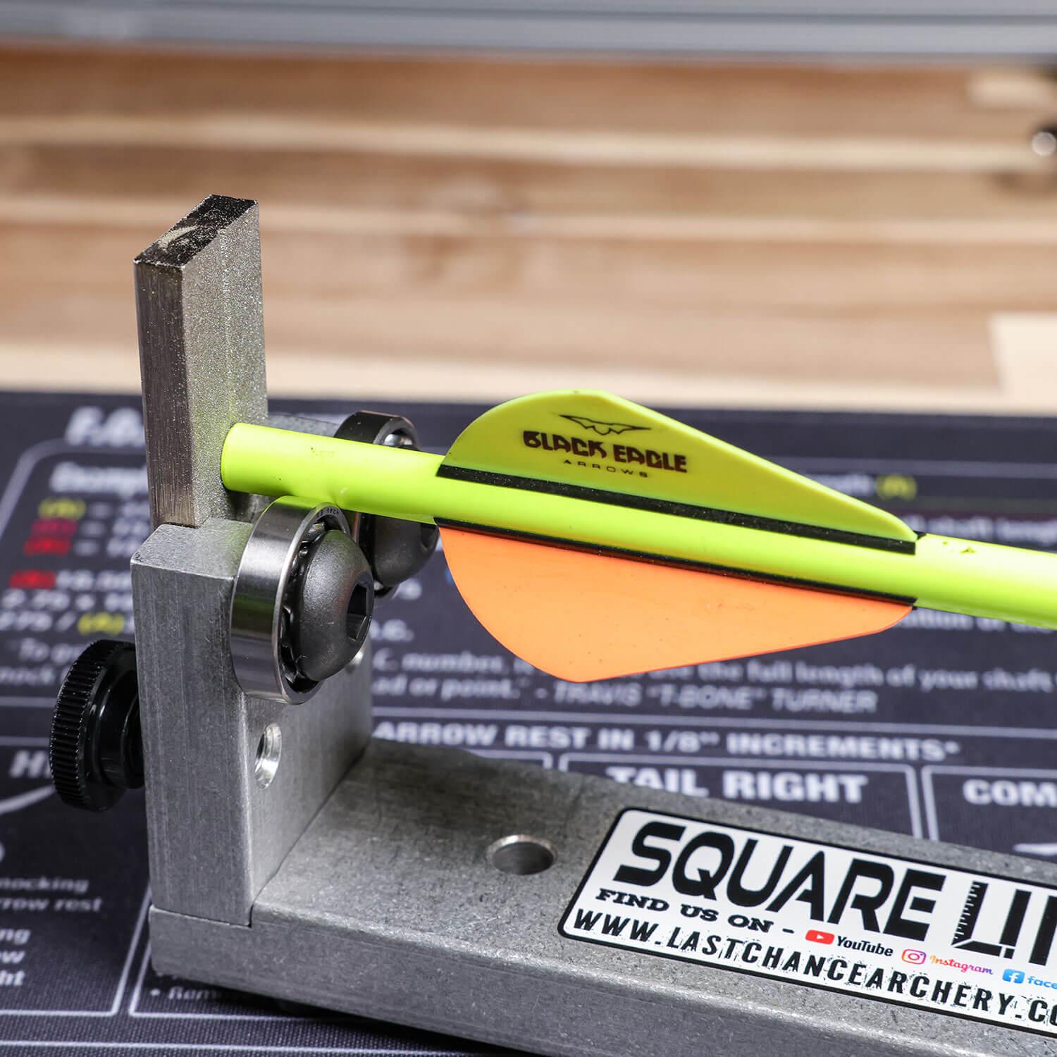 Archery squaring tool aligning a Black Eagle arrow on a workbench
