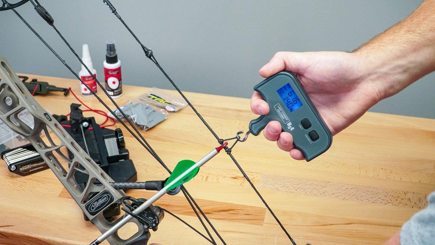 Person using Last Chance Archery HS4 bow peak weight scale to measure compound bow draw weight