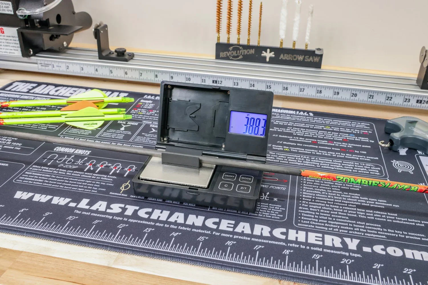 Archery arrow on digital scale with 388.3g reading, measuring mat, and archery tools