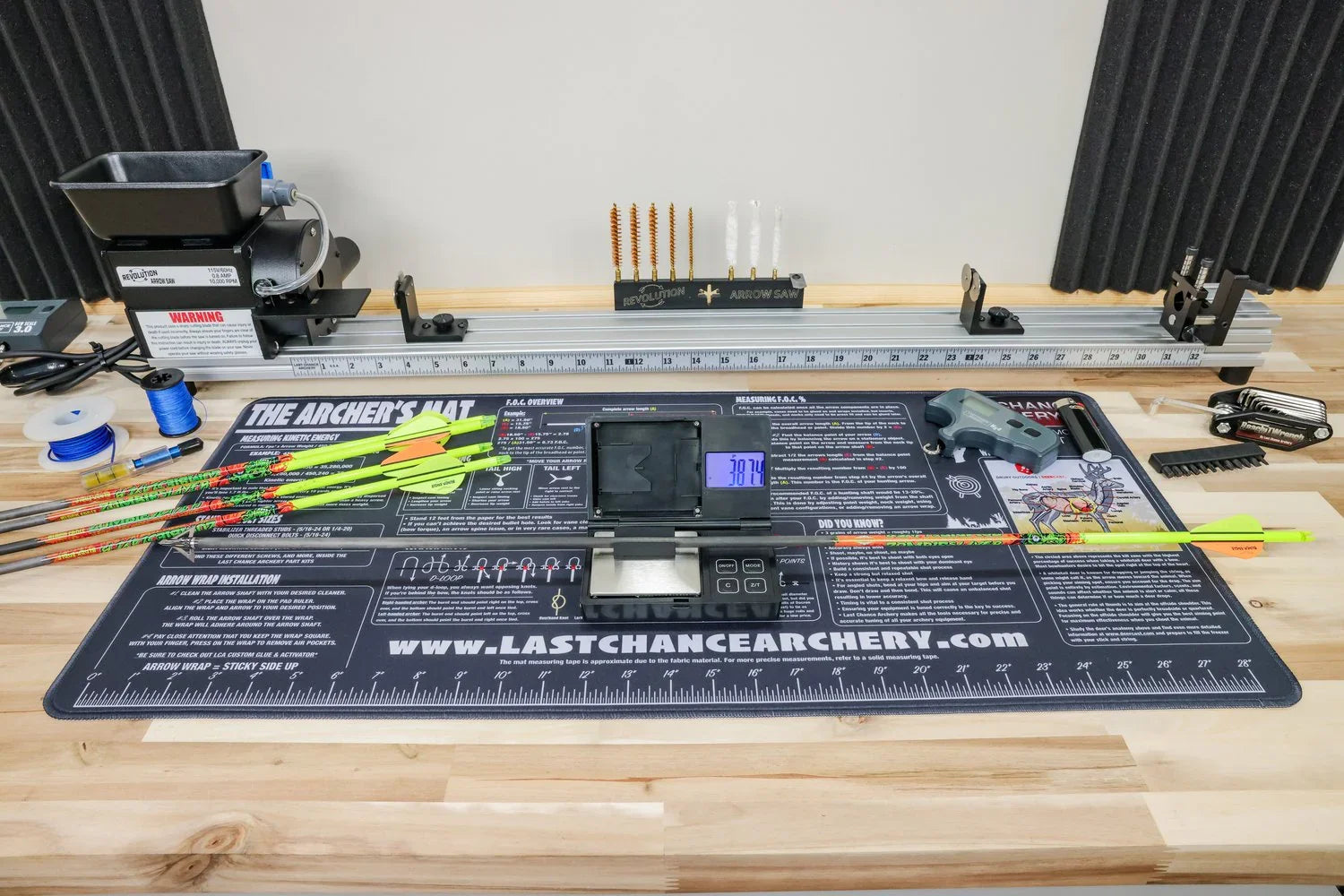 Archery arrow saw on workbench with digital scale, arrows, and bow tuning tools