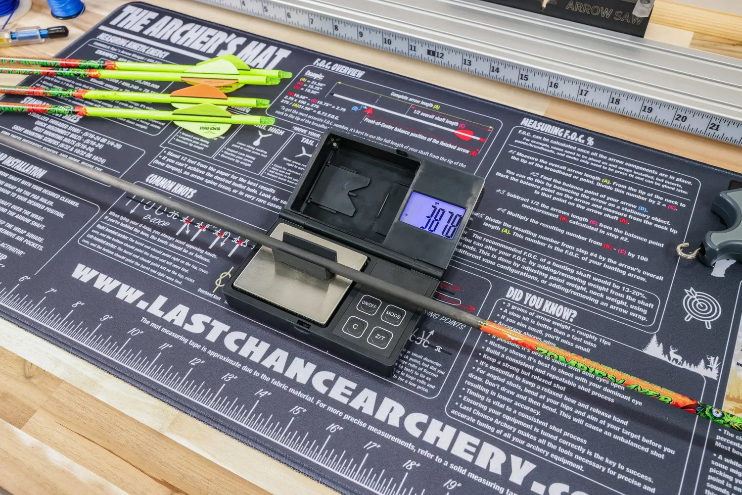 Digital scale weighing archery arrow on Last Chance Archery mat with measuring tools