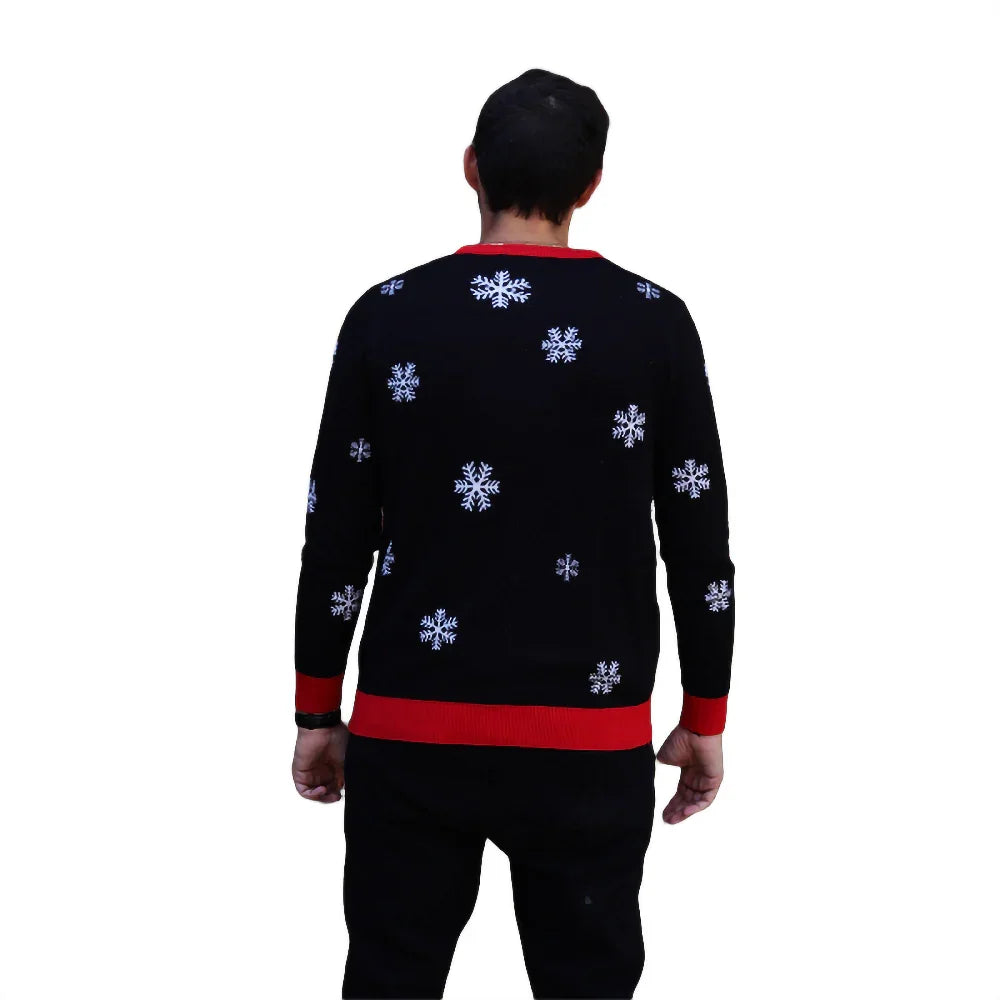 Man wearing black sweater with white snowflake pattern and red trim on white background