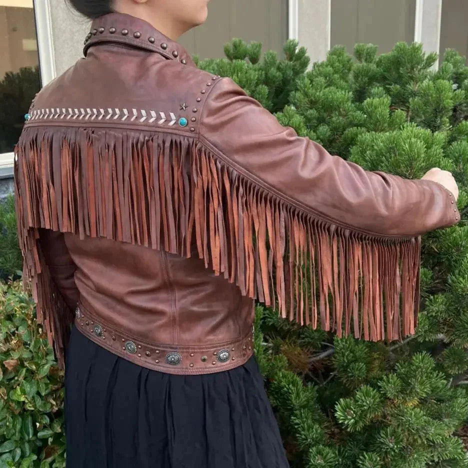 Woman wearing brown leather western jacket with fringe and metal stud details outdoors