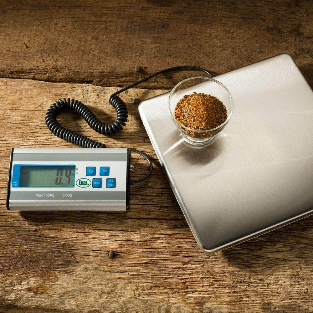 Digital kitchen scale weighing spices in a glass bowl on rustic wooden table